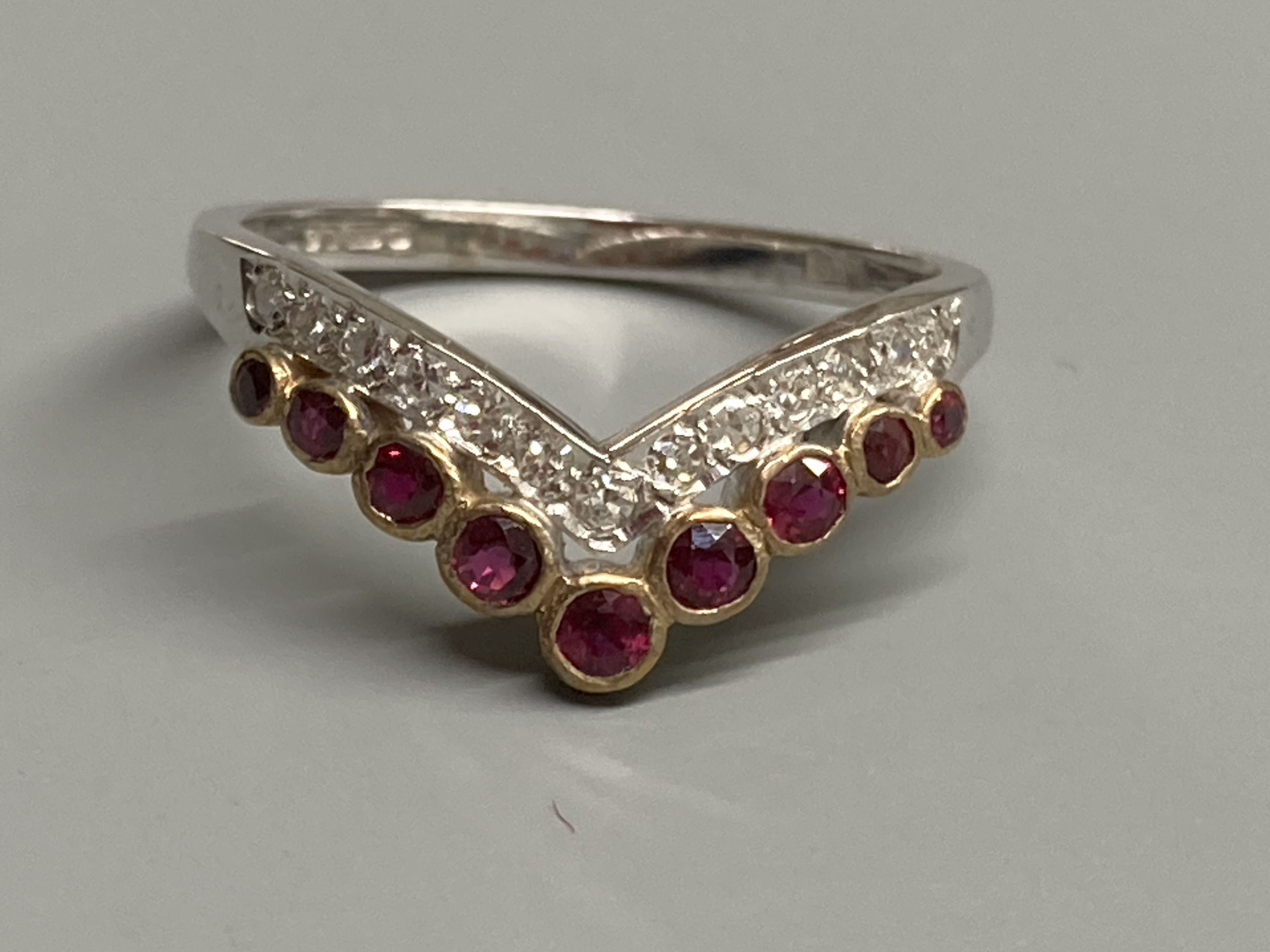 A modern 18ct gold, two row ruby and diamond set chevron ring, size M/N, gross 2.1 grams.
